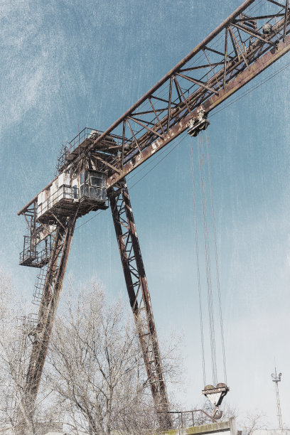 旧的，生锈的门式起重机在铁路上，一个废弃的混凝土工厂。危机、经济崩溃和生产能力的关闭导致了崩溃。全球灾难。一张古老照片的效果。图片下载