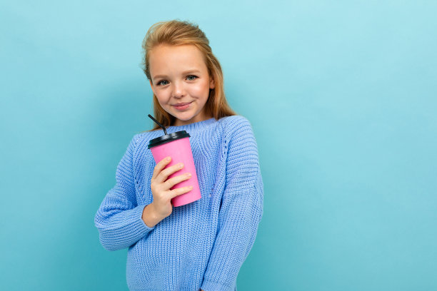 一个欧洲女孩的肖像，拿着一个浅蓝色背景的杯子图片下载