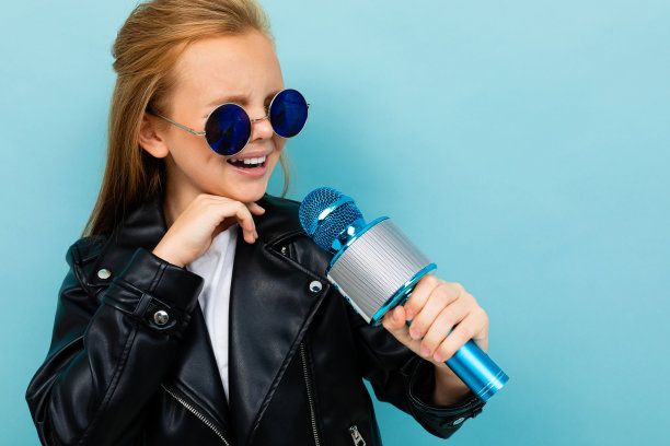 一个迷人的欧洲女孩，穿着皮夹克，戴着墨镜，用麦克风唱着淡蓝色的背景图片下载