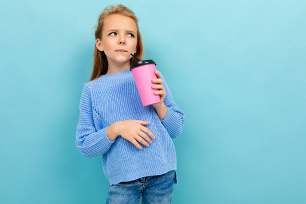 一个漂亮的欧洲女孩的肖像，拿着一个浅蓝色背景的杯子图片下载