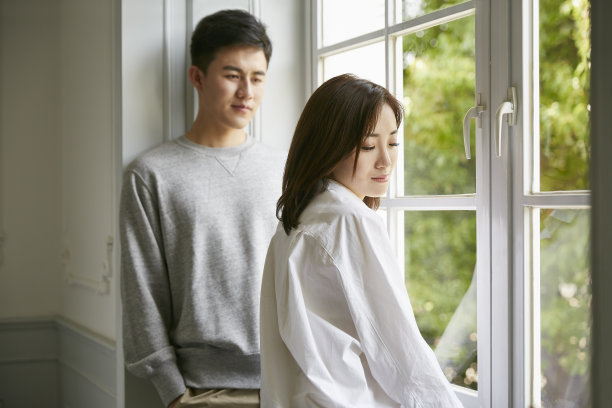 年轻的亚洲夫妇站在窗边交谈图片下载