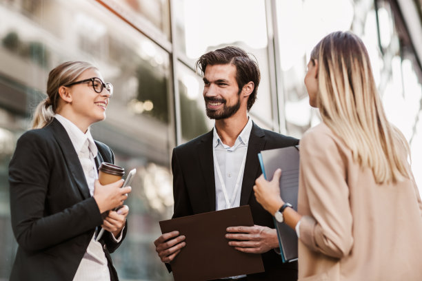 办公大楼附近的商务人士在室外交谈。素材图片