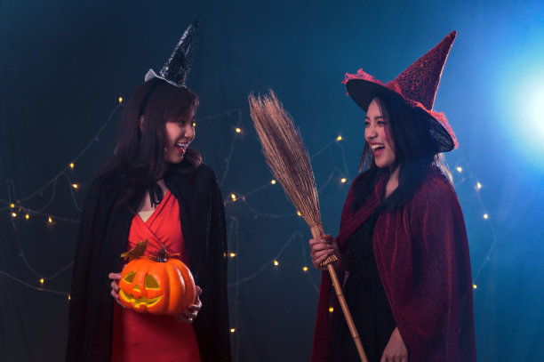 两个美丽的年轻女人的肖像在女巫万圣节服装在黑暗的魔法背景下的派对-万圣节派对的概念图片下载