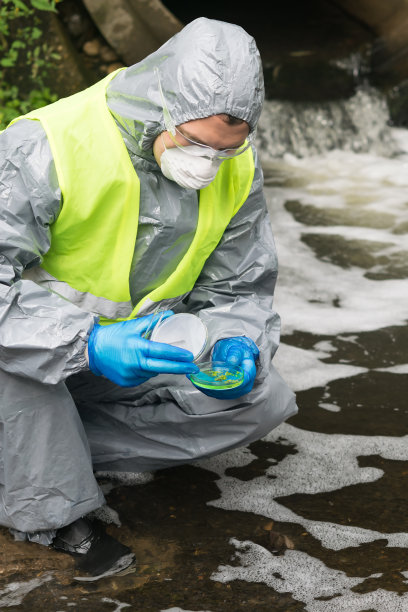 一名穿着防护服的男子拿着一个装有植物样本的培养皿，在加入试剂后观察培养皿中的反应图片下载