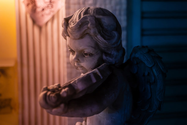 一尊天使般的雕像和一把小提琴放在屋前的角落里。图片下载