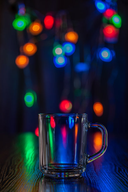 木桌上的空杯子，在彩色灯光模糊的背景下。这个节日前夕。的概念。图片下载