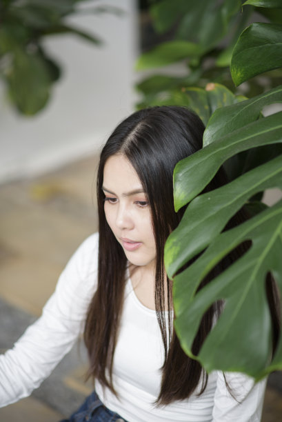 一个穿着白衣的年轻女子的肖像和绿色植物图片下载