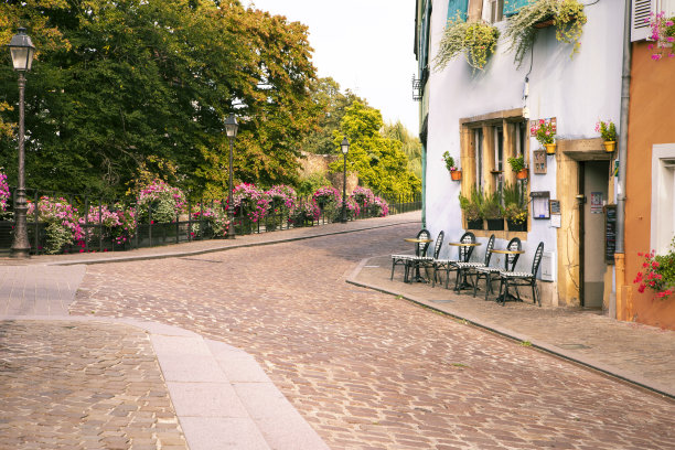 风景浪漫的法国鹅卵石街道，咖啡馆，街灯和公园的背景。在法国阿尔萨斯的科尔马，五颜六色的建筑外立面上的空桌子和椅子图片下载