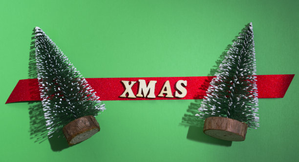 圣诞贺卡。两棵圣诞树，送上祝福。红色云杉上写着“圣诞节”。绿色背景。图片下载