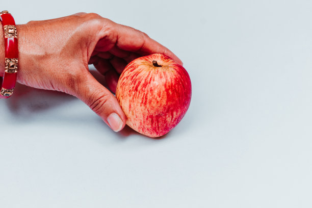 俯视图的女性手拿着红苹果孤立在白色的背景。带有文本空间图片下载