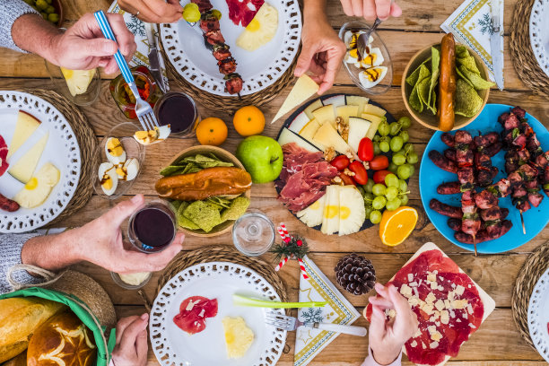 圣诞庆祝木桌满食物装饰和人们有乐趣在一起-家庭传统和朋友在家里或餐厅吃圣诞午餐或晚餐图片下载