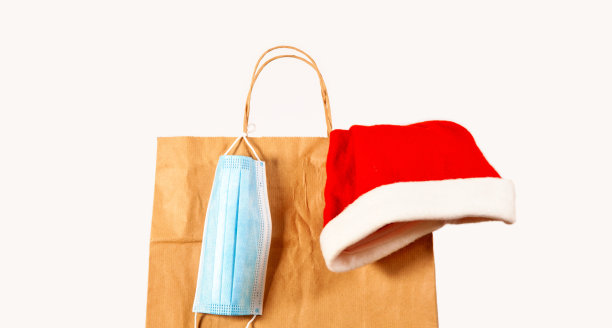 配备圣诞帽和医用口罩的圣诞购物袋。图片下载