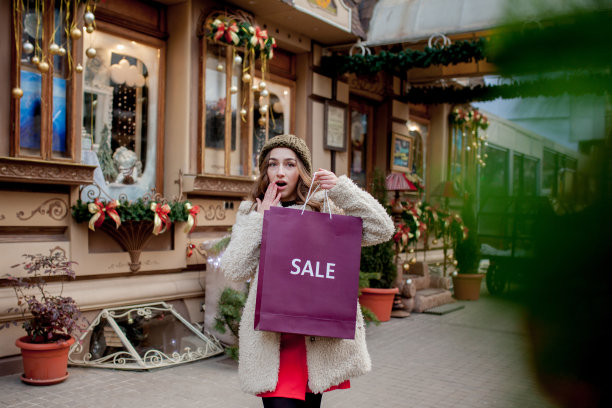 快乐的女孩拿着印有销售标志的纸袋在圣诞节的商店里，在城市周围。购物理念，节日快乐，圣诞销售。图片下载