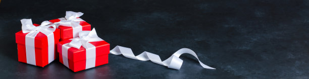 带有白色丝带的红色礼品盒。黑色的具体背景。副本的空间。图片下载
