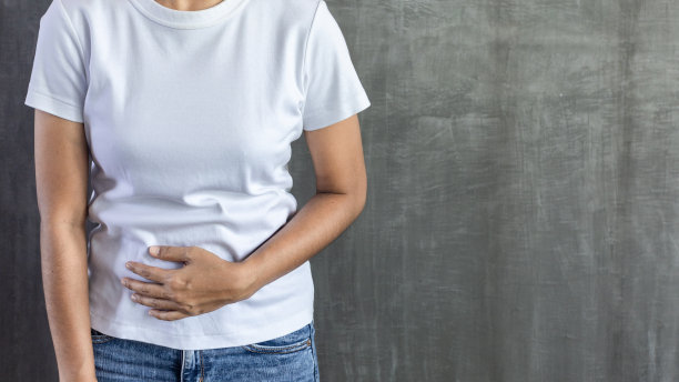 年轻女子胃痛在灰色混凝土墙的背景图片下载