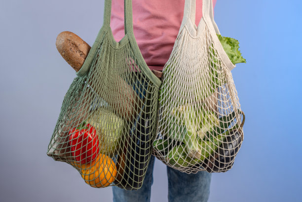 现代的年轻人拿着一个装着商品的网袋。环保的行为理念，使用可重复使用的袋子和关心环境图片下载