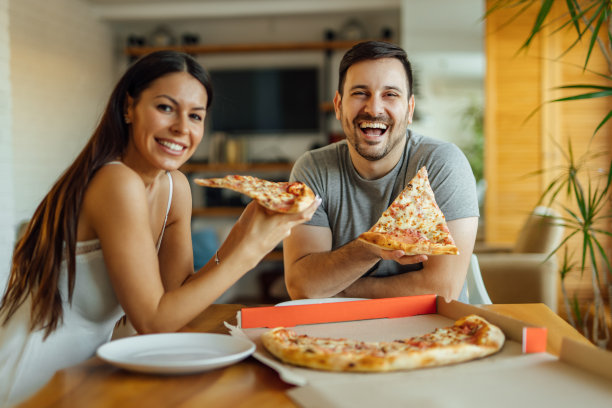 这是一对幸福的夫妇在早上吃披萨的照片。图片下载