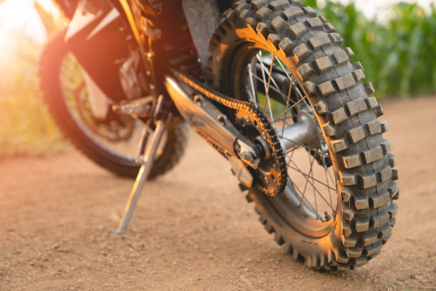 在温暖的阳光下，一辆摩托车在玉米地的土路上行驶。图片下载