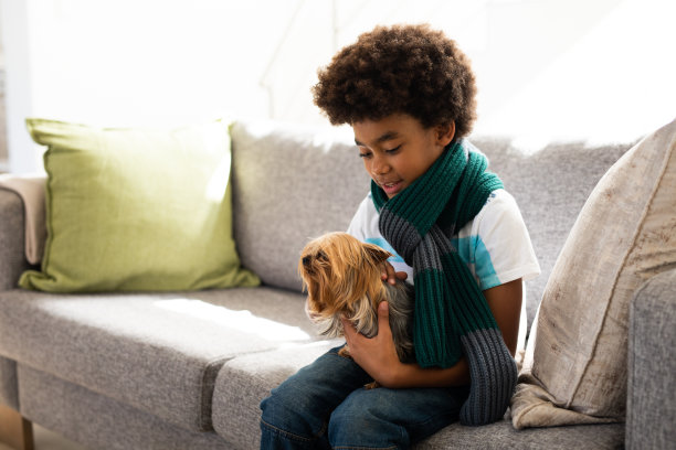 一个小男孩在家里抱着他的小狗狗图片下载