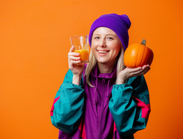 漂亮的女人穿着90年代的运动服，橙色的背景是南瓜汁图片下载