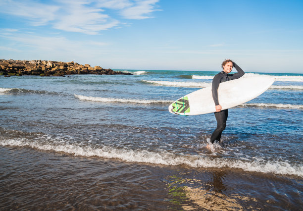 冲浪者带着冲浪板进入水中。图片下载