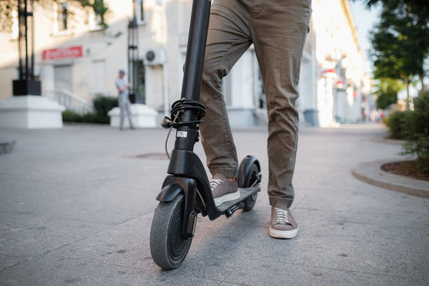 男子骑黑色电动踏板车在日落的城市景观的特写图片下载