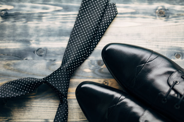 黑色领带与白色圆点和男人的皮鞋在一个木制的背景。图片下载