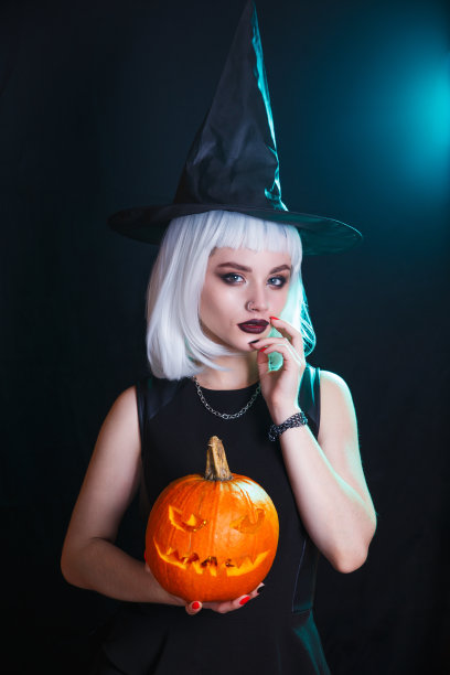 万圣节女巫与雕刻的南瓜在黑暗的背景图片下载