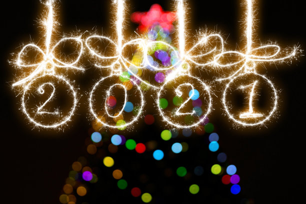 圣诞球由烟花和碑文2021的背景下，多色的散焦从新年树的灯光。图片下载