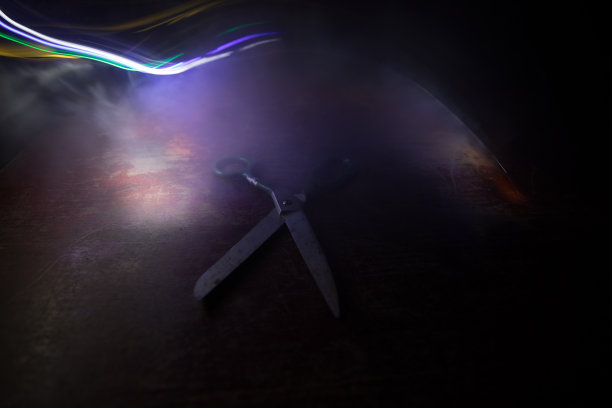 在昏暗的光线下，把裁缝的剪刀放在木桌上。艺术品装饰与色调朦胧的背光。图片下载