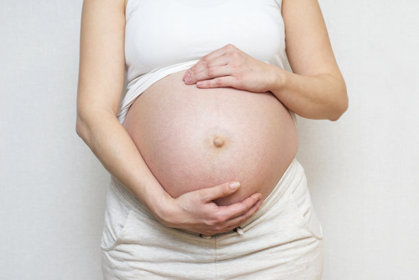 孕妇在灯光背景下双手放在肚子上。怀孕、分娩、准备和期望概念。特写，复印空间，室内。美丽柔情的怀孕照片图片下载