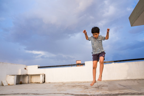 一个6岁的孩子在美丽的蓝天背景下自信地从一个高度跳下，对所涉及的风险漠不关心图片下载