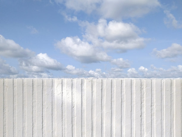 半正面视图下的白色垂直条纹石膏热带蓝色的天空。白色粗糙的水泥墙与垂直肮脏的线条。混凝土墙体竖向条纹图案设计。法属西印度群岛。图片下载