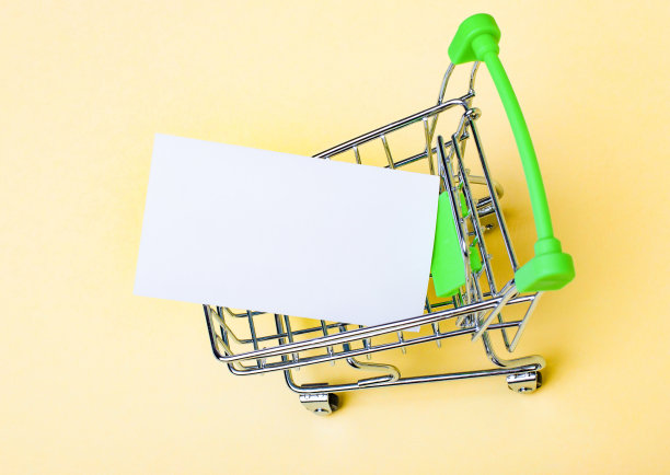 米色背景上，一个购物车和一个白色空白的名片。本空间图片下载