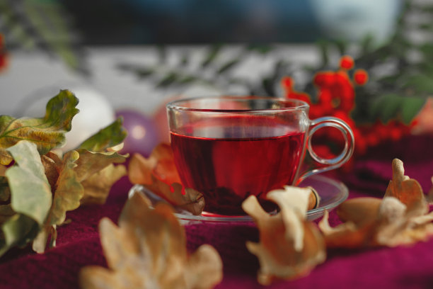 玻璃杯与茶在紫色编织的背景与秋叶图片下载