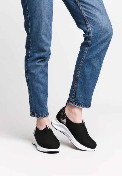 白色背景下穿着黑色运动鞋的女人腿。鞋子广告照片的概念图片下载