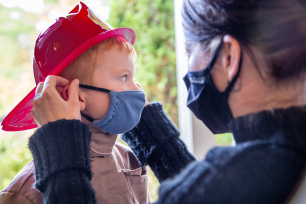 2019冠状病毒病大流行前夕，母亲给孩子戴上防护口罩图片下载