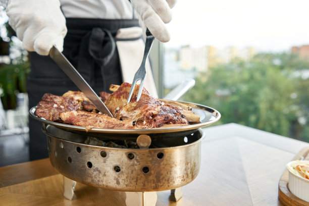 侍者正在用刀切肉。各种烤肉套餐。烧烤餐厅的菜单，一系列不同肉类的照片。图片下载