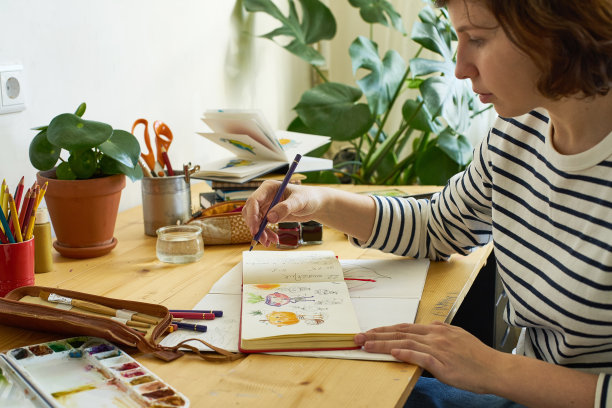 特写图像的艺术家画在一个速写簿。女性设计师在家工作。创造舒适的工作场所图片下载