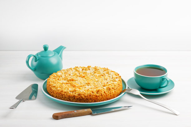 白色木桌上放着杏仁花瓣的苹果派和一杯茶。Copyspace。素材图片