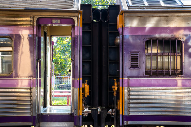 侧面的火车车厢与银色和紫色和黑色的通道停车在一个火车站。图片下载