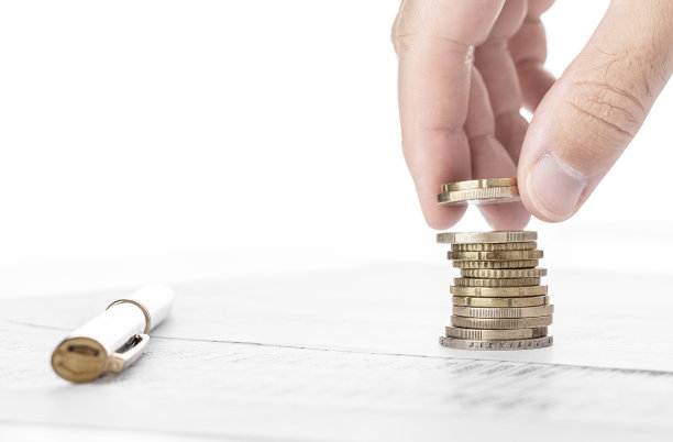 商人在金融数据上数钱和堆硬币。财务、会计和银行概念。素材图片