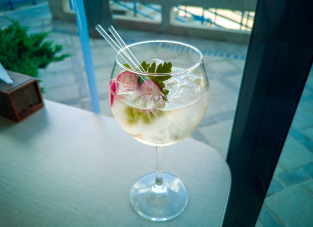 酒吧桌上的酒杯里装着鸡尾酒。美丽的白色鸡尾酒，加冰，欧芹和萝卜在桌上。图片下载