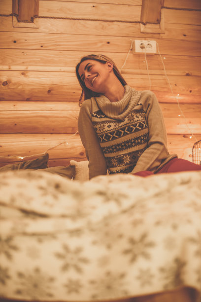 一个悠闲的女人坐在一个木制房间的床上图片下载