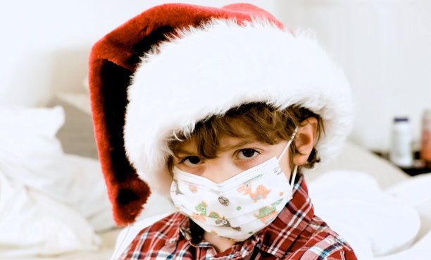悲伤的小男孩戴着圣诞老人帽和防护面罩看着镜头图片下载
