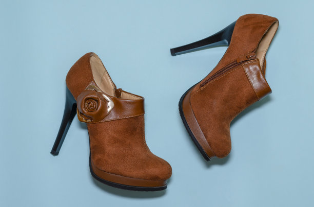 棕色女性的脚踝靴与高跟鞋在一个蓝色的背景。图片下载