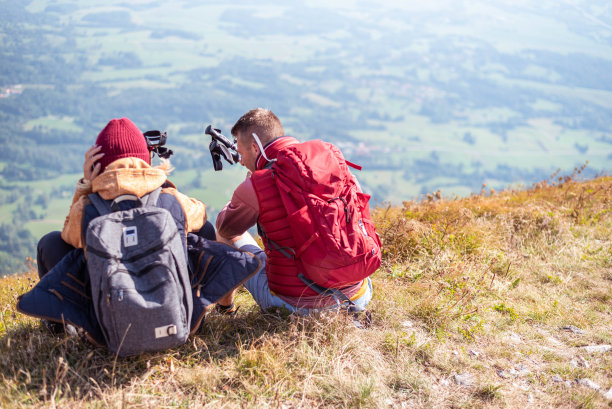 后视图的成年夫妇坐在山顶和休息图片下载