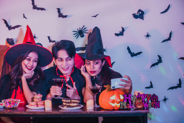 万圣节派对概念-快乐的人们与万圣节的巫婆服装和德古拉斗篷享受自拍时间!最好的朋友在万圣节派对之夜自拍图片下载