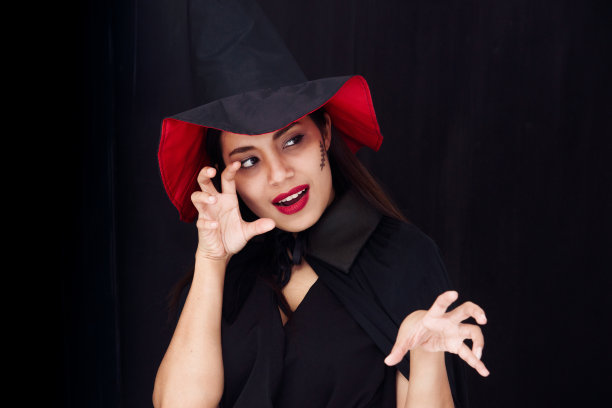 万圣节派对女孩。万圣节女巫明亮的妆容和长发。美丽的年轻惊讶的女人摆着女巫性感的服装。孤立在黑色背景上图片下载