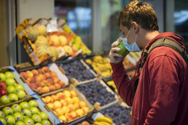 一个年轻的成年人在城市街道的露天市场上闻着苹果图片下载